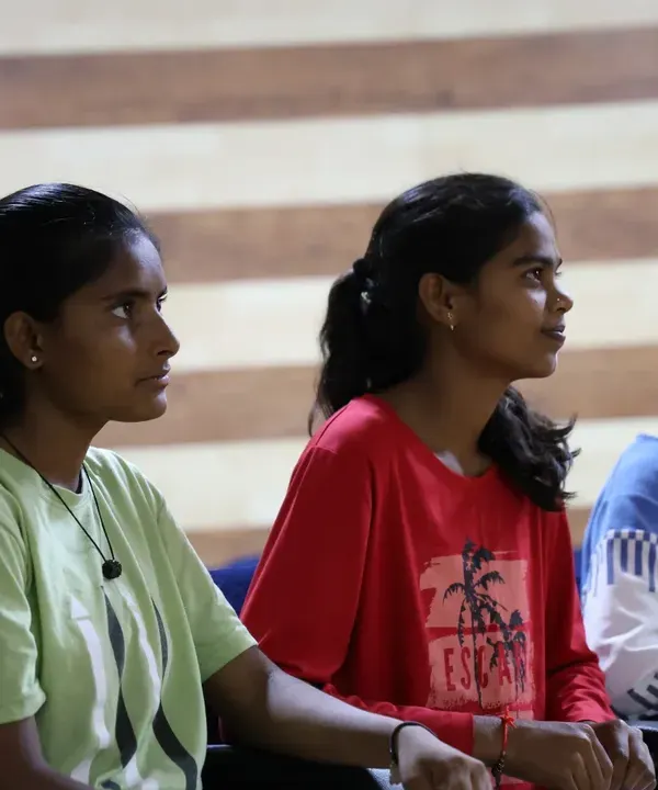 Young athletes at the Anantapur Sports Academy listen intently during a session for the Female Athlete Leadership Program. This image captures the focus and engagement as they absorb lessons on leadership and personal growth.
