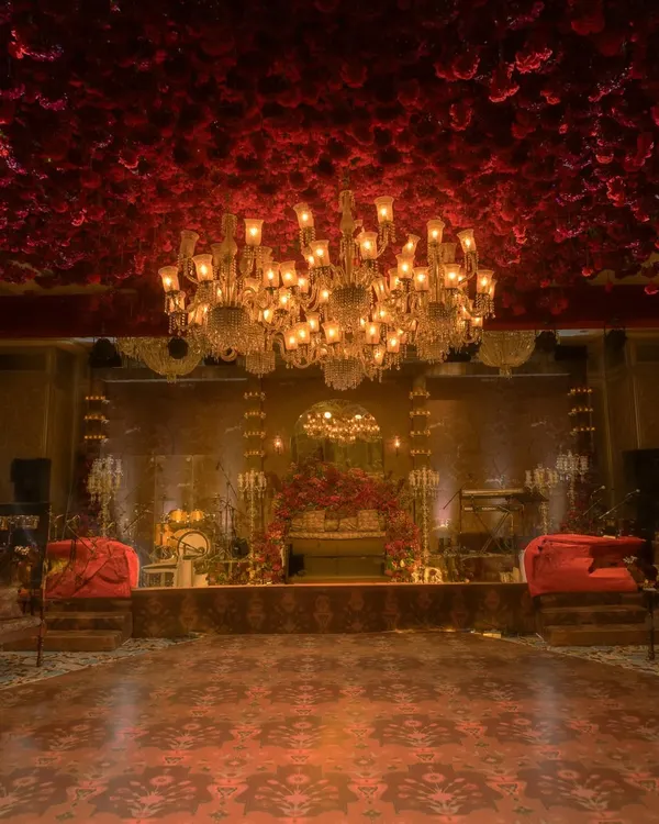 A breathtaking view of a reception hall I designed. The ceiling is completely covered in red flowers, with a magnificent crystal chandelier as the centerpiece, creating an atmosphere of pure opulence and romance.