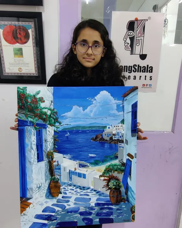 A proud student holds her stunningly detailed acrylic painting of a Santorini seascape. Our step-by-step guidance helps students tackle complex subjects and create artwork they can be proud of.