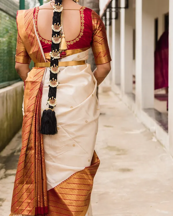 This is the back view of a classic South Indian bridal look, showcasing the perfectly draped Kanjeevaram saree and a traditional 'poola jada' (floral braid) with hair ornaments.