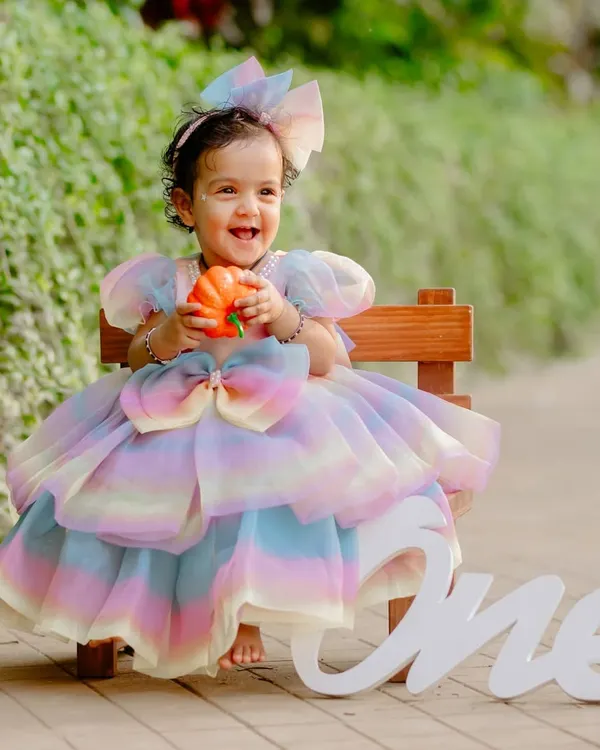 A radiant smile for a magical first birthday. This outdoor shoot uses natural light to highlight the beautiful rainbow dress and the pure happiness of the moment.