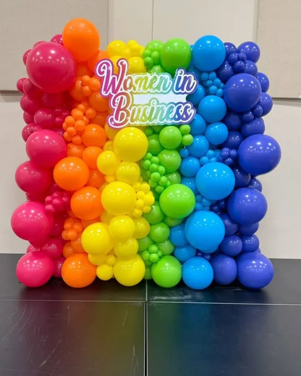 This custom 'Women in Business' backdrop combines a full spectrum of colorful balloons with a bright neon sign. It’s a great example of how we create visually impactful and on-brand photo walls.