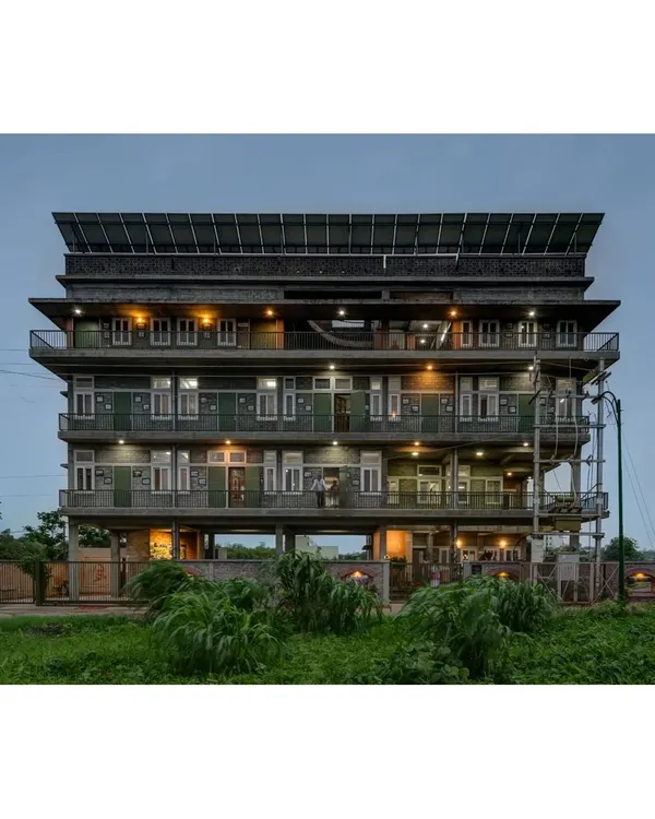 The Action for Social Advancement (ASA) office in Bhopal, illuminated at night. The building is elevated on stilts to handle a water-logged site, and the rooftop is covered with a 20kVA solar PV system, making it energy self-sufficient.