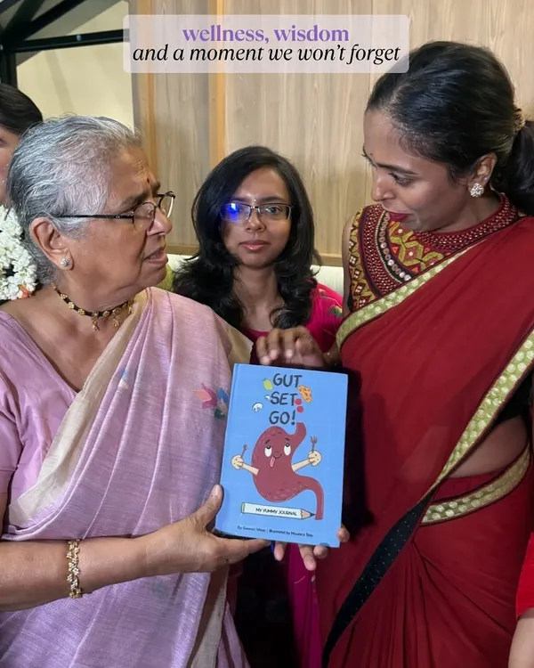 A heartwarming moment of me gifting my book, "Gut, Set, Go!", to an elder, showing the intergenerational appeal of wellness.