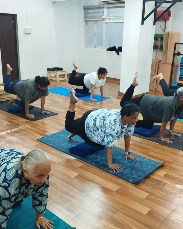 Our Golden Age Yoga class is all about joyful living. Here, our senior members practice a gentle leg lift to improve balance and core stability.