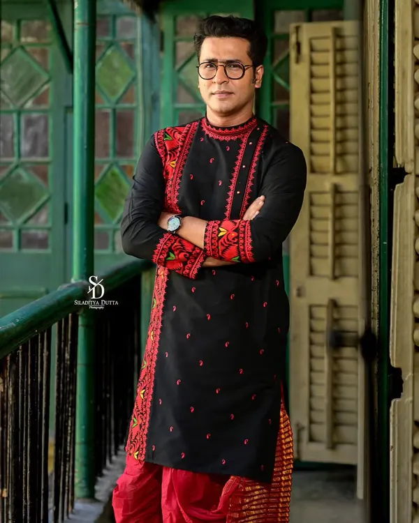 A strong, confident portrait of the groom in a striking black and red embroidered kurta. The traditional attire is given a modern edge with this powerful pose.