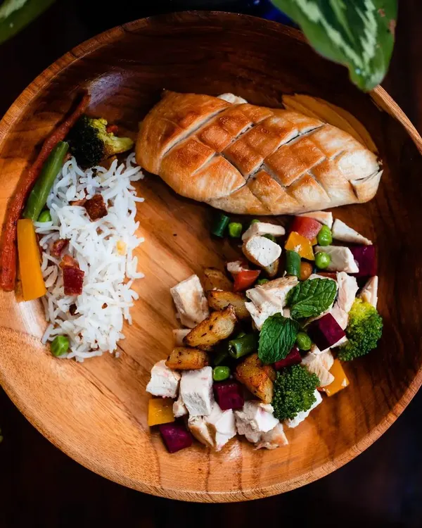 This is my signature Chicken Steak meal, plated to show you exactly what your pet gets. It features a pan-seared chicken breast, a side of rice with bacon bits, and a fresh salad of chicken, potatoes, and mixed vegetables. It's a complete, balanced, and delicious meal.