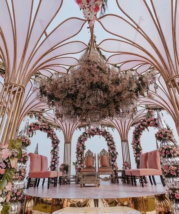 A full view of Yasha and Rahil's stunning seaside mandap. The open, airy structure allowed the natural beauty of the ocean to become part of the decor, while the blush florals and intricate design added a layer of romance and elegance.