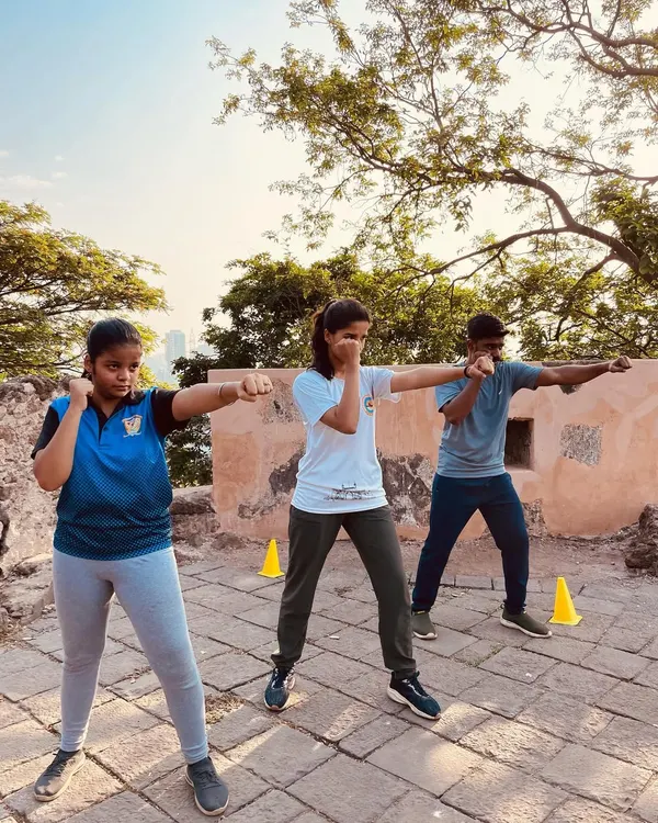 This is where we forge warriors. Our outdoor training sessions, like this one at a historic fort, are designed to build resilience and adaptability. Here, students practice their kickboxing stance and punches, learning to focus amidst the elements.