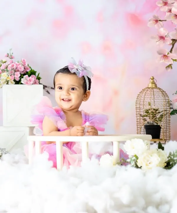 A dreamy fairy-tale scene with a beautiful little girl in a pastel dress. The cherry blossom backdrop and fluffy clouds create a magical, ethereal atmosphere.