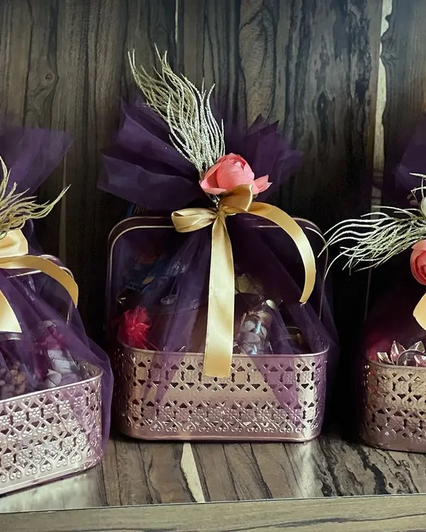 A trio of luxurious Diwali hampers wrapped in deep purple tulle with gold ribbons and floral accents. These are perfect for premium client gifting during the festive season.