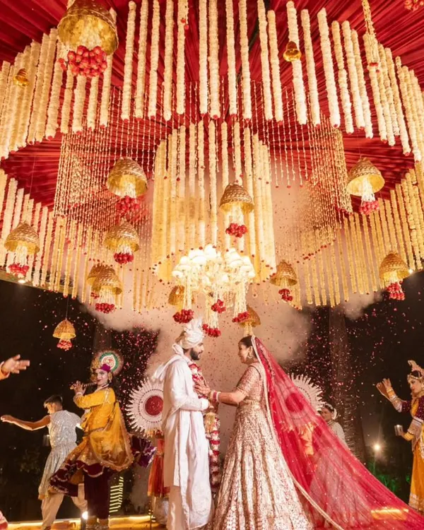 A breathtaking varmala moment, where the couple is framed by a magnificent floral chandelier crafted from thousands of tuberoses. This is the pinnacle of a royal wedding, a memory suspended in time and enchantment. ✨