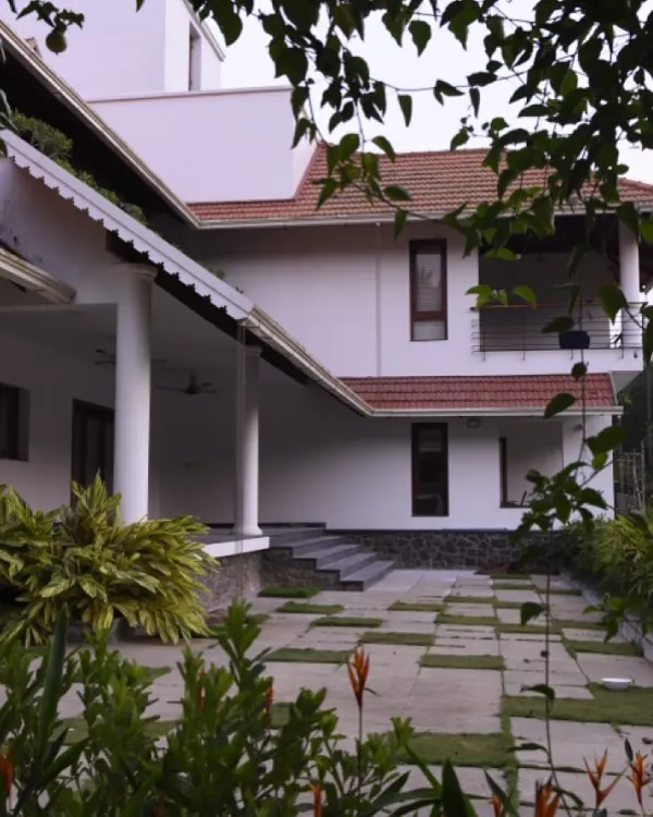 The estate house for Mr. Alex in Thrissur features expansive verandas supported by classical columns. This design provides ample shaded outdoor living area and reflects traditional Kerala architectural styles, adapted for modern living.