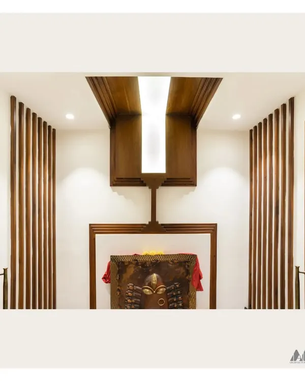 The interior of the Pooja room before placing the idols. The design features a dramatic wooden ceiling element with a central light, flanked by vertical wooden slats that add texture and warmth.