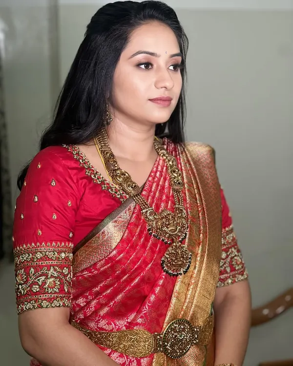 Embracing timeless elegance with a dewy, minimal look. This bride's natural glow is the star, enhanced with soft makeup. Her royal red silk saree and temple jewellery are perfectly complemented by soft, loose waves.