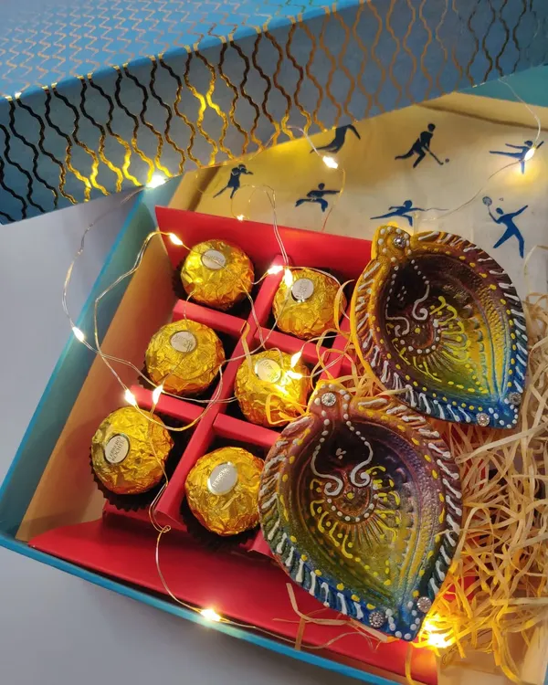 A custom Diwali hamper I put together, featuring hand-painted diyas, chocolates, and fairy lights. I love creating personalized gift boxes for special occasions.