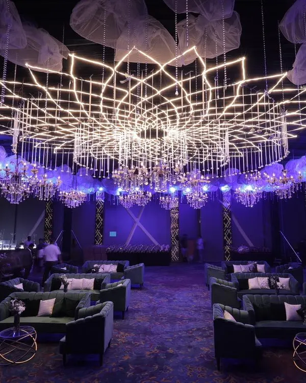 A custom-designed geometric lighting installation creates a breathtaking centerpiece for a large-scale corporate gala. This setup, featuring plush velvet seating and ambient purple lighting, demonstrates our ability to transform large venues into immersive, high-end environments.