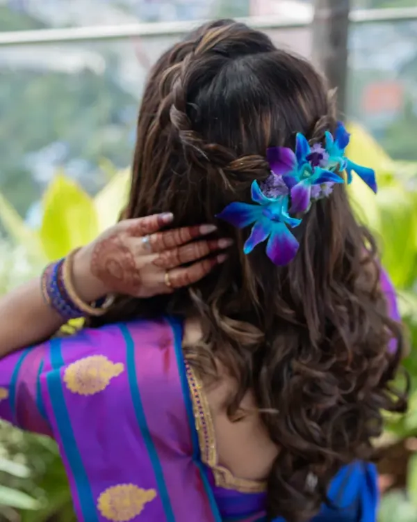 A beautiful look for a baby shower. The makeup is soft and glowing, with a braided hairstyle adorned with fresh orchids.