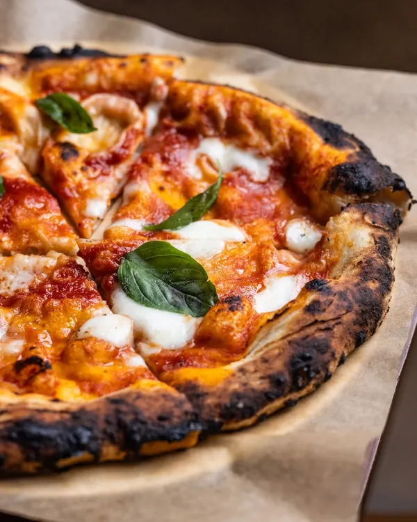 This is what a real Neapolitan pizza should look like. The crust is perfectly charred from my wood-fired oven, the San Marzano tomato sauce is vibrant, and the fresh mozzarella and basil bring it all together. This isn't just a pizza, it's a classic perfected for you.