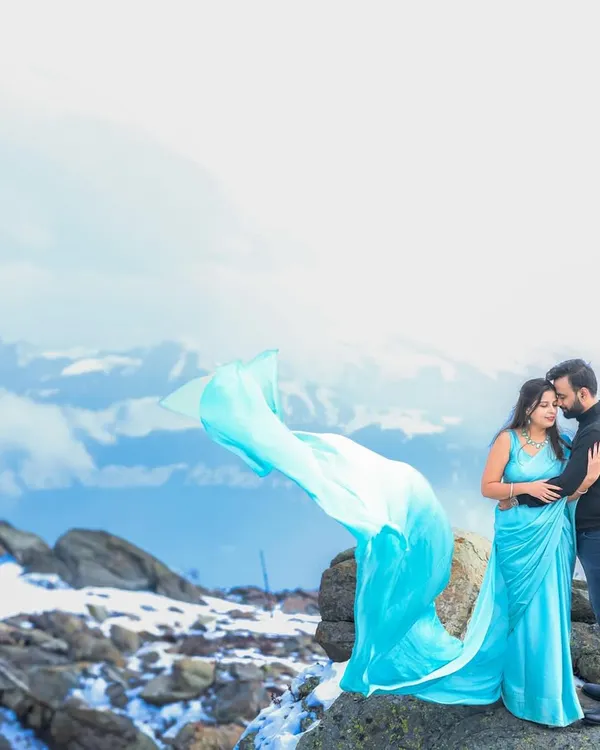 A breathtaking pre-wedding portrait in Gulmarg, Kashmir, with the snowy mountains creating a dramatic backdrop. This shot captures the epic scale and romance of a destination shoot.