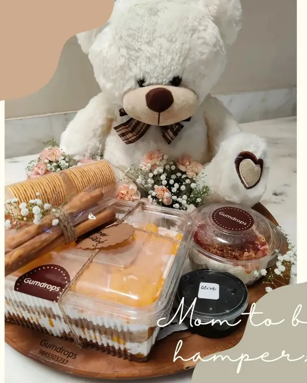 Our special 'Mom-to-be' hamper, featuring a cute teddy bear alongside delicious treats like Mango Pudding, Paprika Garlic Cream Cheese, crackers, and olives.