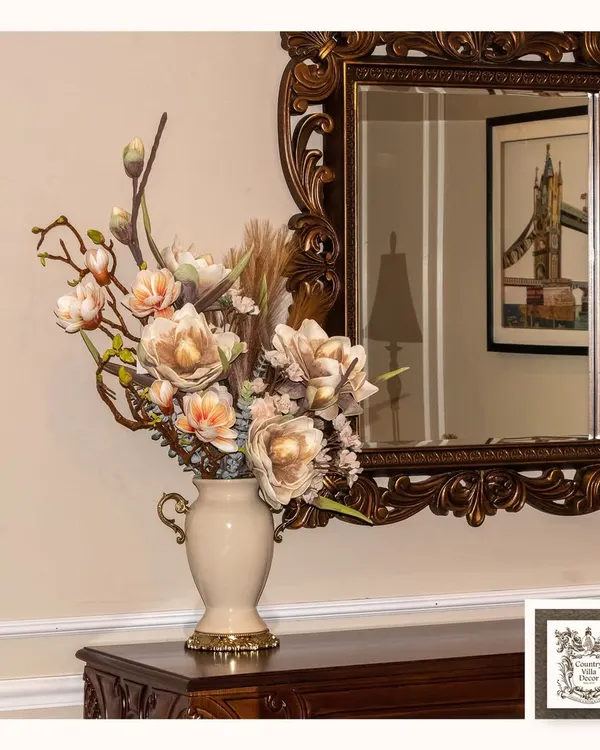 This rich, ornate mirror serves as a beautiful backdrop for a classic floral arrangement. Its detailed frame adds a vintage and elegant atmosphere, reflecting the beauty of the room.
