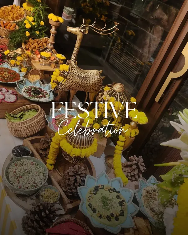 A festive celebration table adorned with yellow marigolds and brass decor. The spread includes a variety of Indian and fusion dishes, perfect for a Teej or Mehendi function.