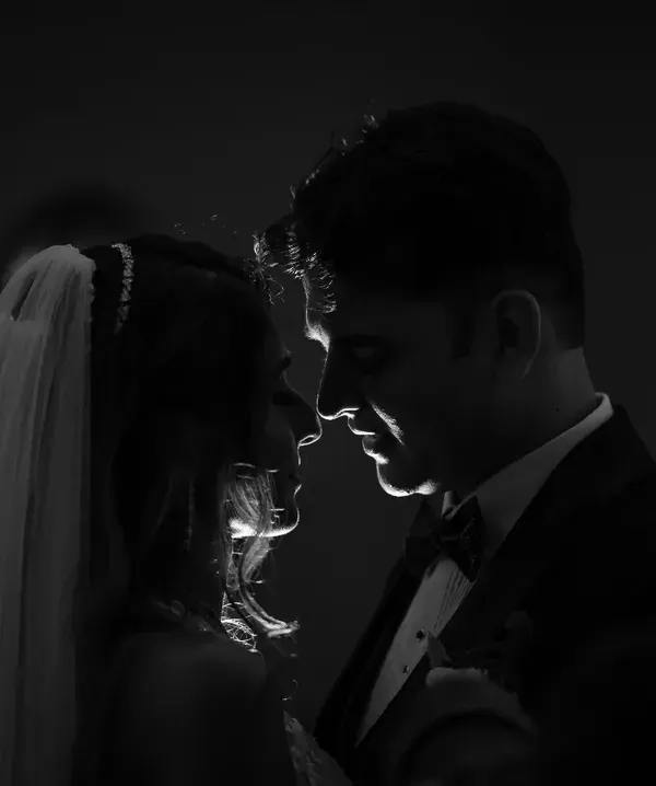 Using shadow and light to create a dramatic, intimate silhouette. This black and white portrait has a timeless, old-Hollywood feel, focusing purely on the couple's connection.
