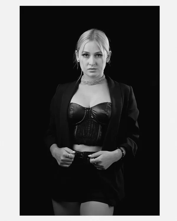 A classic black and white portrait with a strong, direct gaze. The simple styling and clean background put all the focus on the model's expression and confidence.