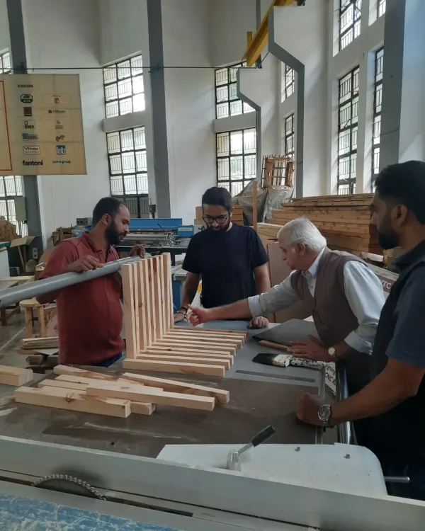 Our approach is built on mentorship. Here, an expert trainer provides one-on-one guidance to students as they assemble a complex slatted furniture piece, ensuring every joint is perfect and every technique is understood.
