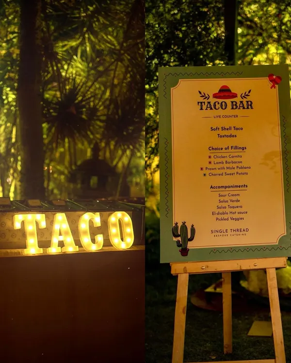 The setup for a memorable taco party. A custom menu board details the delicious fillings and accompaniments, next to our illuminated "TACO" sign, creating an inviting and festive atmosphere for your guests.