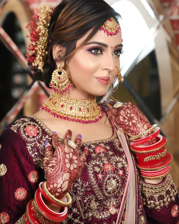 This bride's look is all about royal elegance in a deep wine-colored lehenga. I used shades of purple and pink on her eyes and paired it with a matching choker set for a cohesive, regal look.