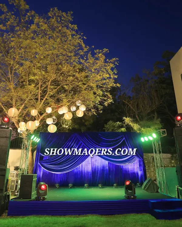 An outdoor stage setup for a corporate retirement party. The royal blue draping, professional trussing with spotlights, and sound system created a perfect setting for speeches and entertainment under the stars.