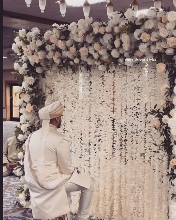 Making your Nikaah ceremony picture-perfect. This elegant setup features a backdrop of white floral strings (mogra) and a lush arch of white roses, creating a serene and beautiful atmosphere for the groom.