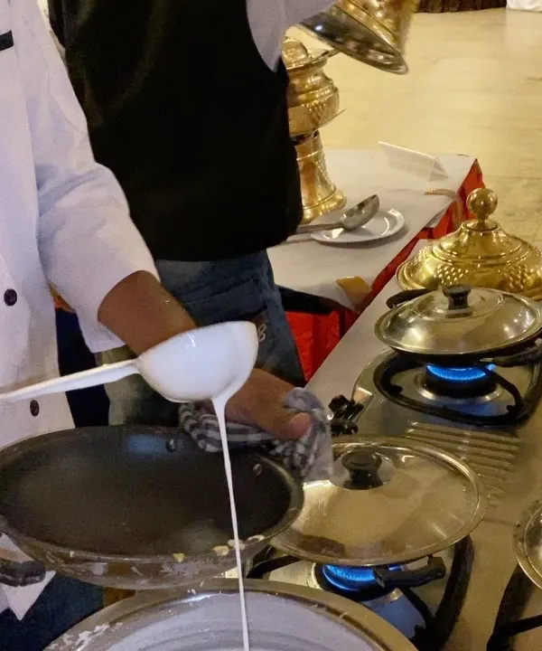 Our chef carefully prepares the batter for a fresh appam at a live cooking station. This is a key part of our South Indian wedding catering service, offering guests an authentic culinary experience.