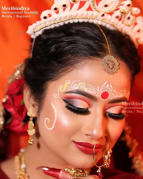 A detailed close-up of the Bengali bridal makeup, focusing on the intricate white and red chandan and kumkum designs that adorn the forehead.