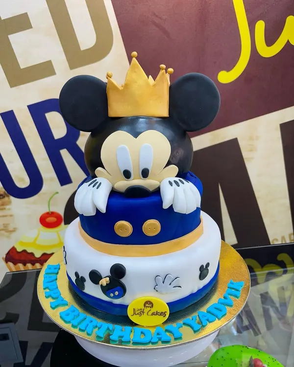A royal Mickey Mouse theme for a special birthday. This 4kg, two-tiered cake features a large, sculpted Mickey head with a golden crown, combining a classic character with a touch of regal flair.