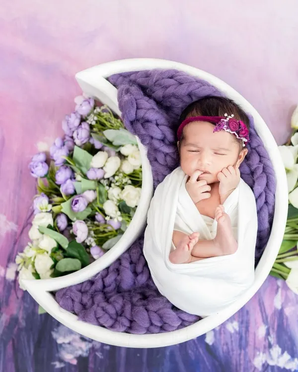 A beautiful newborn portrait using our celestial moon prop with a purple floral arrangement. We have a wide variety of props to create a dreamy setting for your baby.
