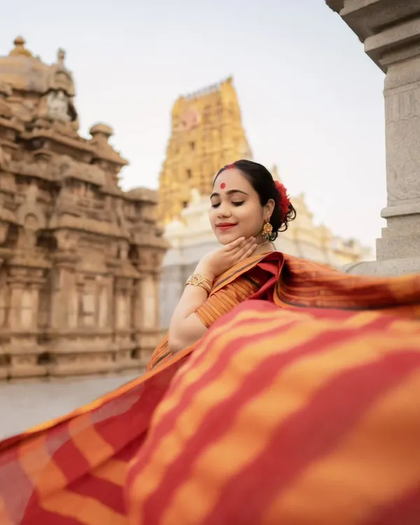 A beautiful moment of peace for this mother-to-be, captured at a historic temple. The flowing red and orange saree adds a touch of grace to this traditional maternity portrait.