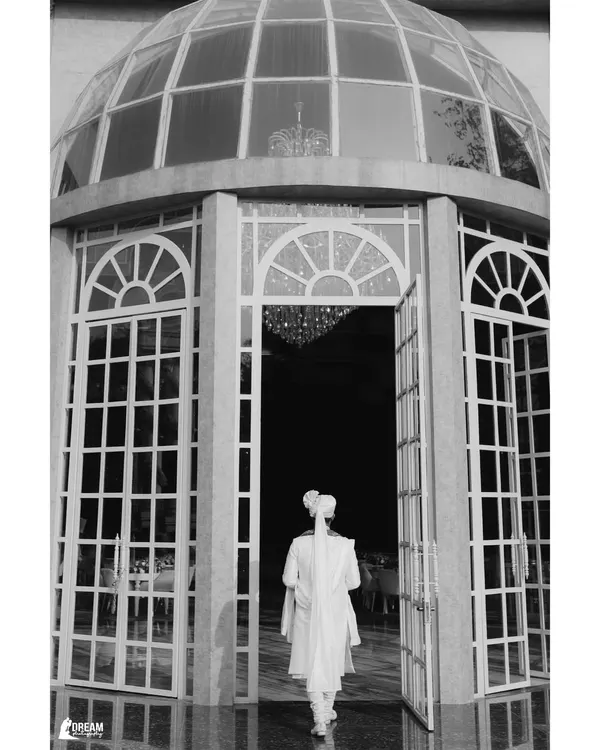 The groom's grand entrance into the wedding venue, a classic black and white shot filled with anticipation.