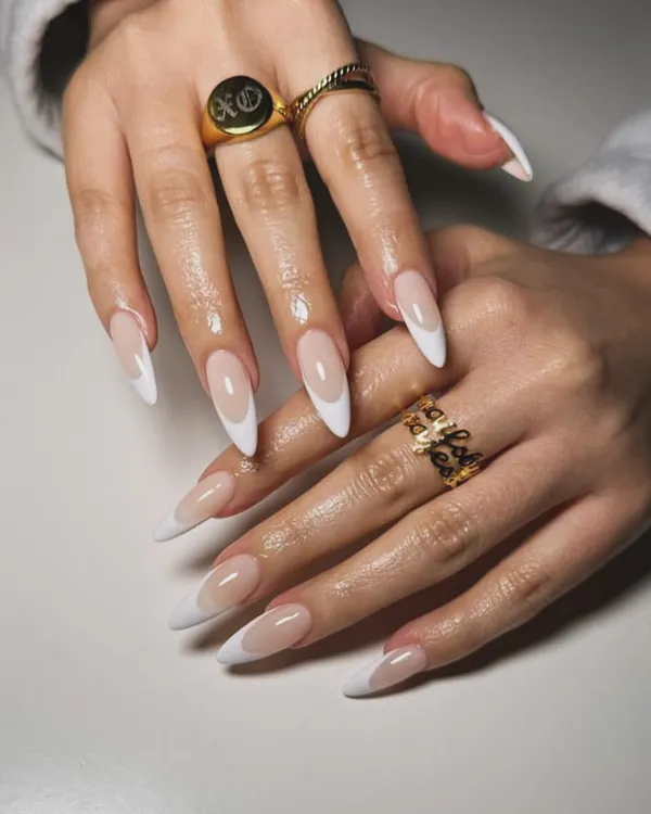 A classic French manicure on long, elegant stiletto-shaped nail extensions. The sharp white tips create a dramatic and sophisticated look.