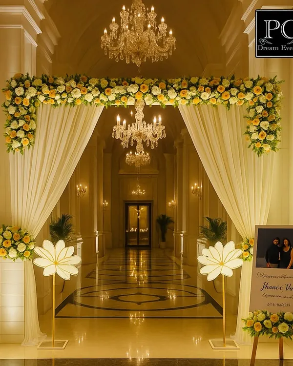 An absolutely regal entrance for an engagement ceremony. I used a floral arch with white drapes, set in a grand corridor with crystal chandeliers, to create a breathtaking welcome for the guests.