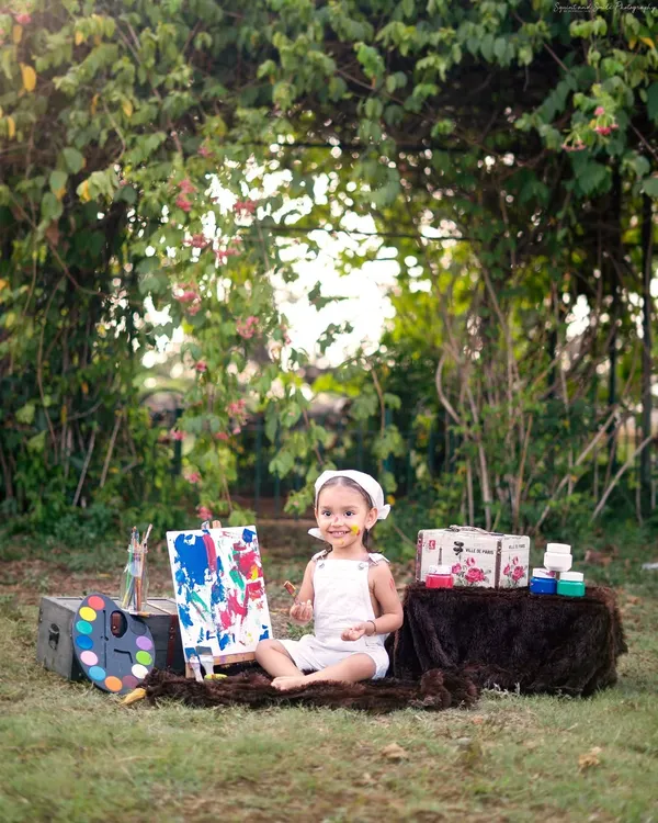 A little artist with a very happy, paint-covered smile. This outdoor painter theme is a fantastic way to capture a toddler's creative and messy side in a beautiful garden setting.