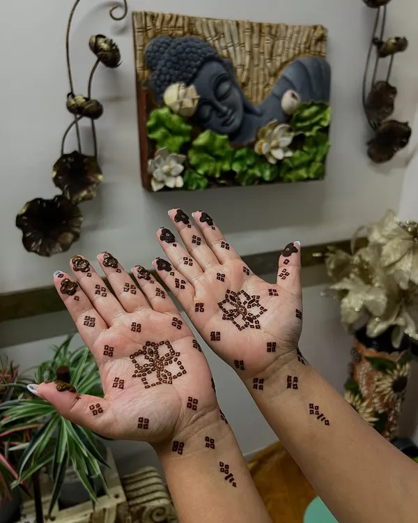 A perfect example of minimal henna for the Teej festival. This design features a simple lotus motif in the center of the palm with small, delicate patterns on the wrist and fingers.