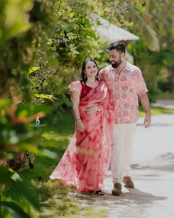 A romantic stroll through a beautiful resort garden. The coordinated floral and pink outfits of the couple complement the lush surroundings.