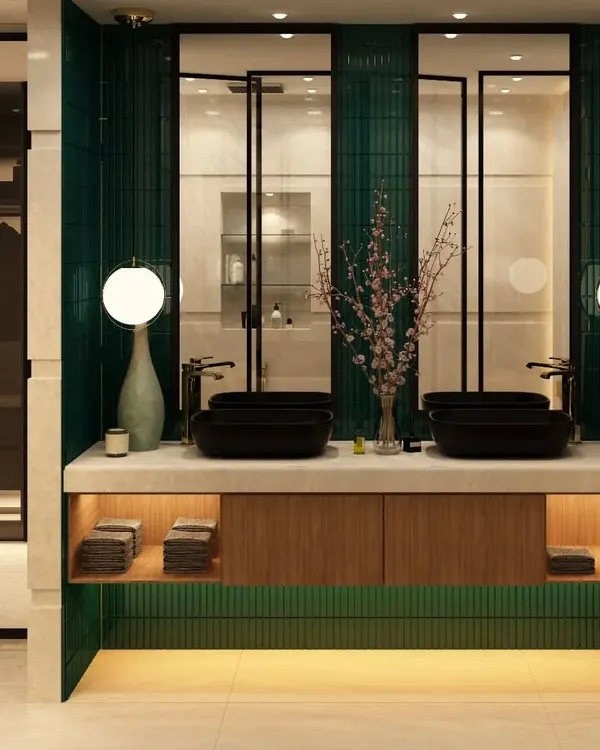 A luxurious double vanity bathroom with emerald green fluted tiles and warm backlighting. The black vessel sinks and globe lights add a touch of modern drama, creating a truly high-end look.