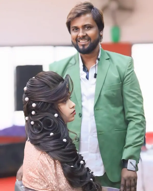 A beautiful party hairstyle with intricate twists and soft waves, decorated with pearls. I am standing proudly next to my creation.