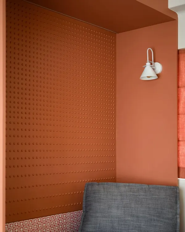 We designed this cozy reading nook in warm terracotta tones with intricate dotted accents on the wall. The snug lounger and stylish planters create a serene, contemporary, and sleek ambiance.