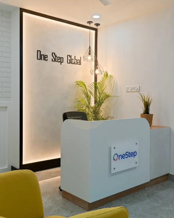 The reception area we designed for Onestep Global's first office in Bangalore. The backlit feature wall with the company logo, modern pendant lights, and a pop of color from the yellow armchair create a welcoming and professional first impression.