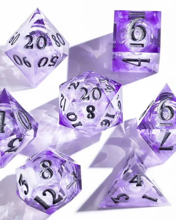 A clean, high-key shot of a set of purple gaming dice. We used hard light to create sharp shadows and highlight the intricate details and numbers on each die, making them pop against the white background.